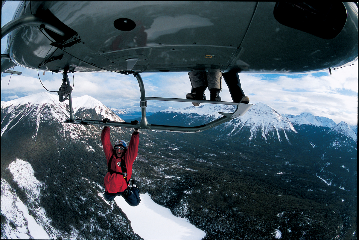 Shane McConkey hanging from a helicopter.