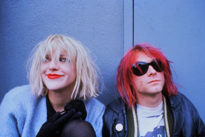 Kurt and Courtney sit against a wall.